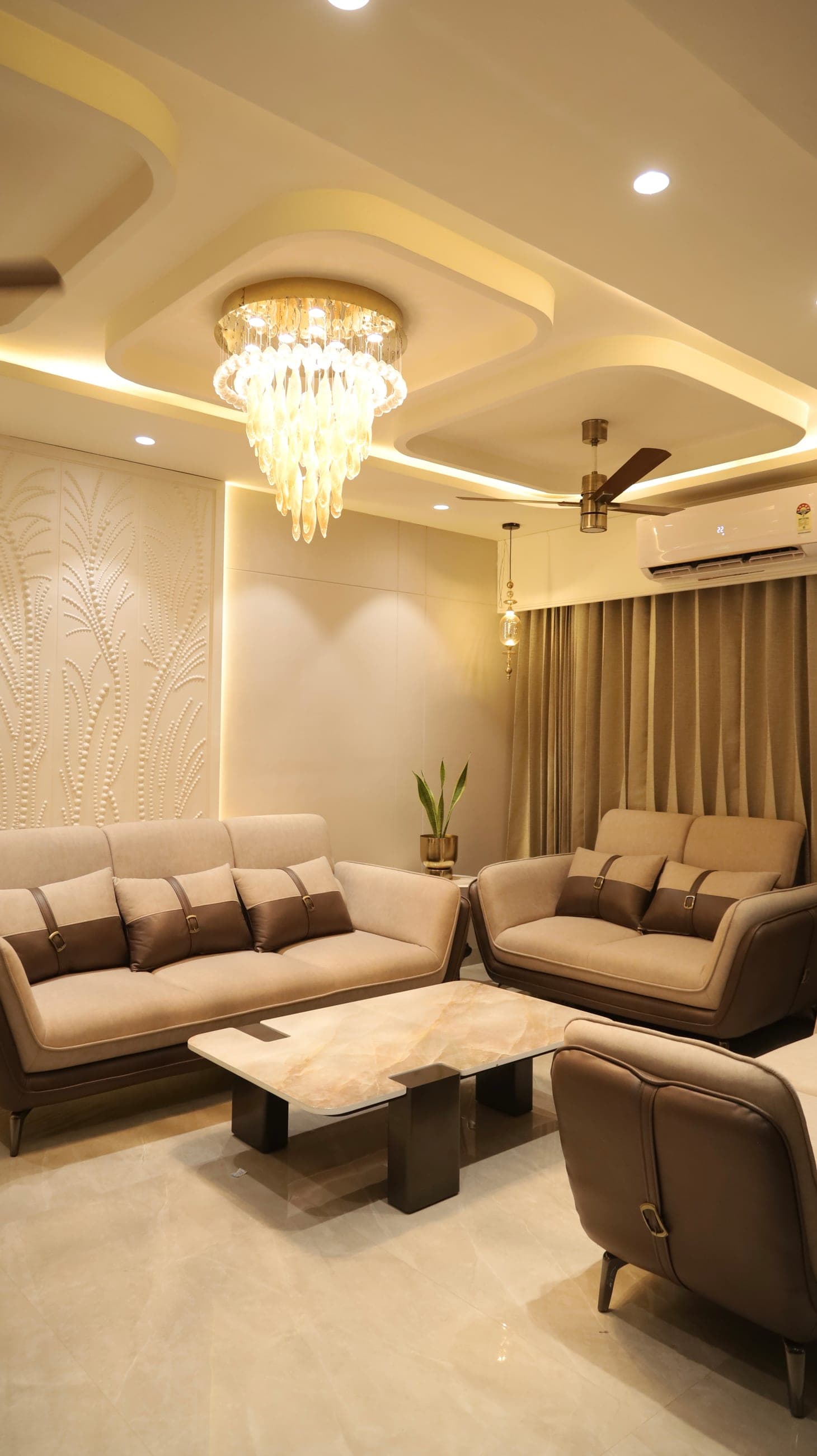 A well-planned living room with layered seating, a feature wall and a chandelier